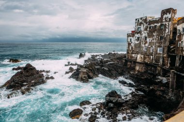 Okyanusta eski bir ev. Atlantik Okyanusu 'nda Tenerife adasında yerleşim binaları olan kıyıya yakın bir fırtına. Gradyan ve doku ses efektli arkaplan rengi. Puerto de La Cruz