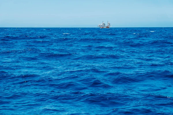 Waves in the Atlantic ocean and a sailboat in the background. Canary islands