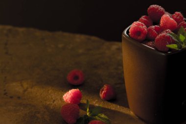 Olgun ahududu siyah arka plan üzerine bir fincan.