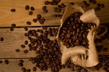 Kavrulmuş kahve çekirdekleri, jute torbasından çiğ tahtalara dökülmüş..