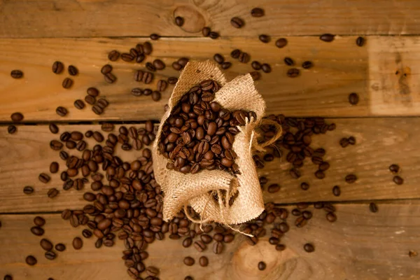 Pieczone Czarne Ziarna Kawy Rozlane Jałowego Worka Surowych Desek — Zdjęcie stockowe