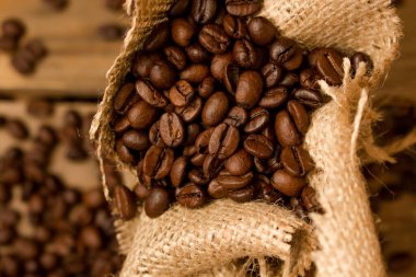 Kavrulmuş kahve çekirdekleri, jute torbasından çiğ tahtalara dökülmüş..