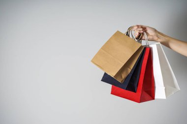 Kara Cuma konsepti. Renkli kağıt, Kraft eko paketleri kadın elinde gri bir arka planda, metin için yer var.