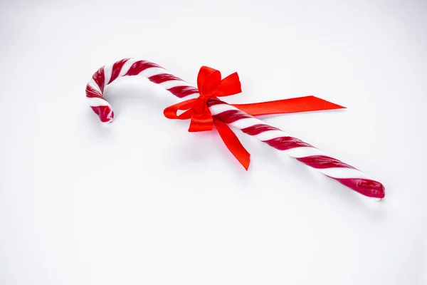 Koncepcja świąt. Świąteczne cukierki z czerwonym łukiem na białym tle. — Zdjęcie stockowe