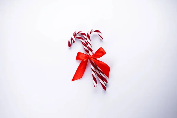 Koncepcja świąt. Świąteczne cukierki z czerwoną kokardą na białym tle. Widok góry. Układy płaskie. — Zdjęcie stockowe