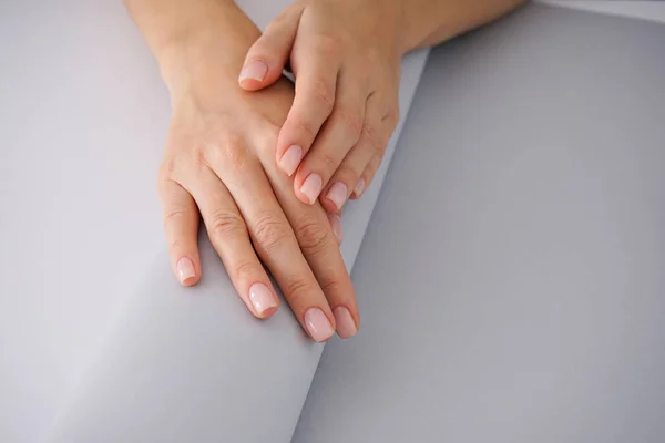 Damskie dłonie z ładnym manicure na biało-szarym tle. — Zdjęcie stockowe
