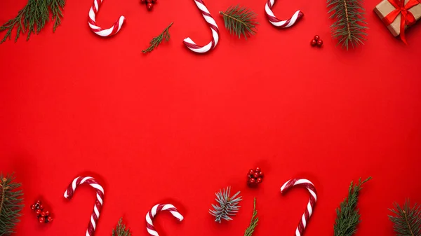 Świąteczna kompozycja. Kompozycja bożonarodzeniowa z cukierkami i świąteczną dekoracją na czerwonym tle, miejsce na tekst. Układy płaskie. — Zdjęcie stockowe