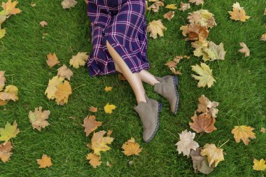 Sonbahar konsepti. Sonbaharda yeşil çimlerin üzerinde bir kızın bacakları. Düz yatıyordu.
