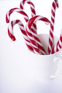 Noel kompozisyonu. Beyaz arka planda, beyaz seramik bir fincanda Noel şekeri. Kapat..