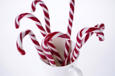 Noel kompozisyonu. Beyaz arka planda, beyaz seramik bir fincanda Noel şekeri. Kapat..