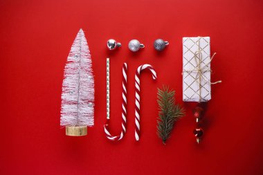 Noel kompozisyonu. Kırmızı arka planda Noel süsleri ve şekerlerin olduğu bir Noel kartı. Düz yatıyordu.