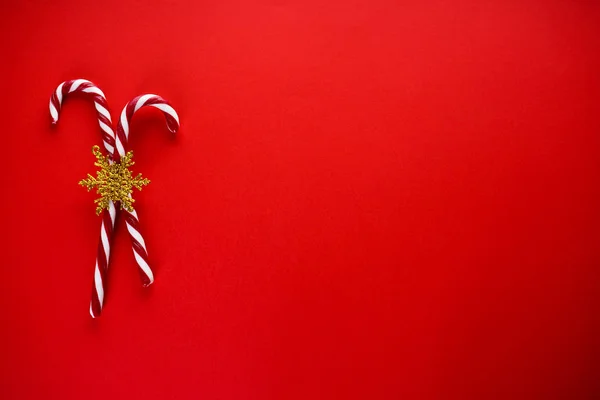 Świąteczna kompozycja. Boże Narodzenie dwie cukierki ze złotym płatkiem śniegu, na czerwonym tle. Miejsce na tekst, płaskie ułożenie. — Zdjęcie stockowe