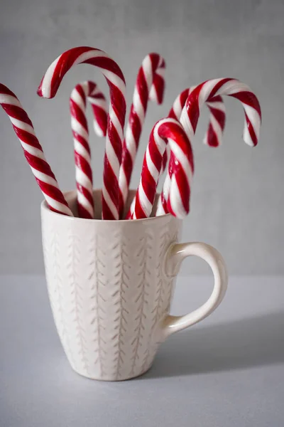 Christmas concept. Christmas candies in a white ceramic cup on a gray background. — Stock Photo, Image