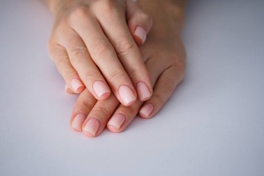 Gri arka planda iyi manikürlü bir kadın eli. Yakın plan. Spa konsepti.