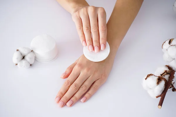 Spa concept. Hands of a young woman with a cotton branch, cotton pads on a white background. Female manicure. Cotton flower. — Stock Photo, Image