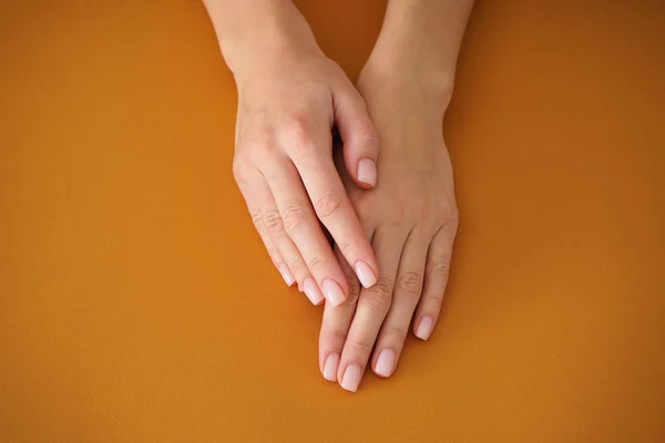 Ręce młodej kobiety z pięknym manicure na beżowym tle. Kobiecy manicure. Zbliżenie. — Zdjęcie stockowe