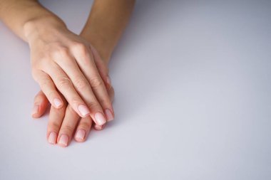Gri arkaplanda yazı için güzel bir manikürlü kadın elleri.
