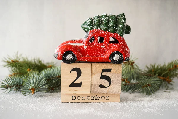 Świąteczna kompozycja. Red Christmas zabawki samochód na starym drewnianym kalendarzu na szarym tle z gałązką jodły. — Zdjęcie stockowe