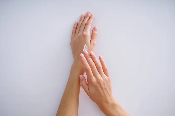 Kremalı kadın elleri ve gri arka planda güzel bir manikür. Spa tedavisi.