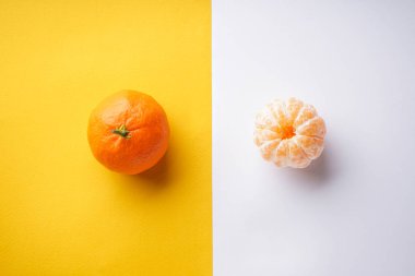Mandalina turuncusu ve beyaz ve sarı bir arka planda soyulmuş. Düz yatıyordu. Yukarıdan görüntüle.