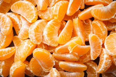 Koyu bir zemin üzerinde olgun mandalina dilimleri yatıyordu..