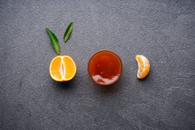 Yeşil yapraklı, yarım mandalina ve koyu arkaplanda reçel. Düz yatıyordu.