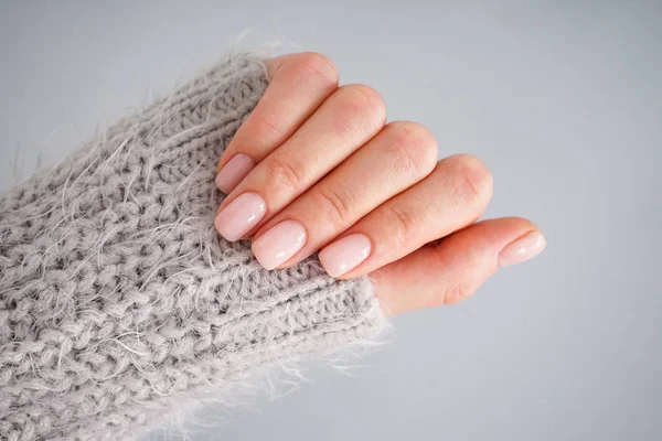 Flat lay. Hand of a young woman with beautiful manicure on a gray background. Female manicure. Close-up.