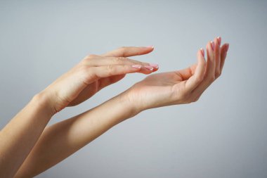 Spa ve Manikür konsepti. Gri bir arka planda güzel manikürlü genç bir kızın güzel elleri.