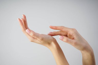 Spa ve Manikür konsepti. Gri bir arka planda güzel manikürlü genç bir kızın güzel elleri
