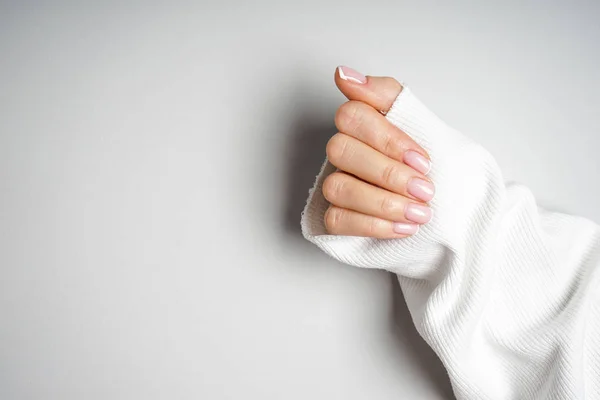 Winter care, skin, spa concept. Beautiful hand of a young girl with beautiful manicure on a gray background, place for text. — ストック写真