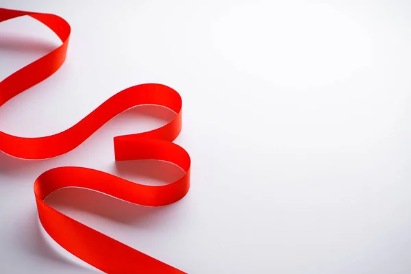 Rood lint in de vorm van een hartje op een witte achtergrond met plaats voor tekst. Stockfoto