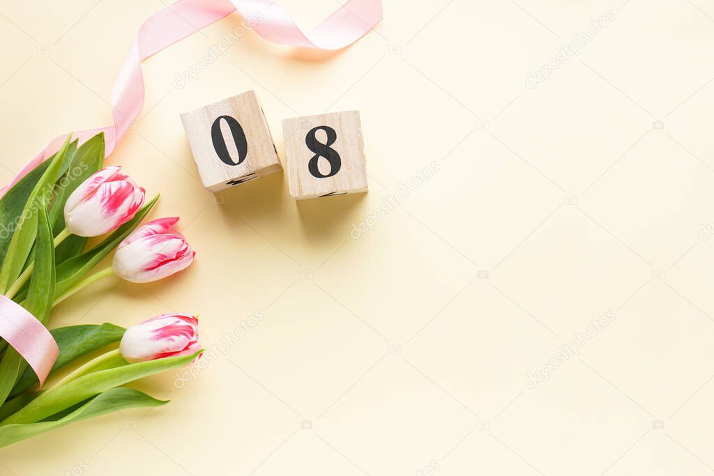 Women's day, a bouquet of fresh tulips in a pink ribbon with a wooden calendar on a yellow background. 8 March, International Women's Day.