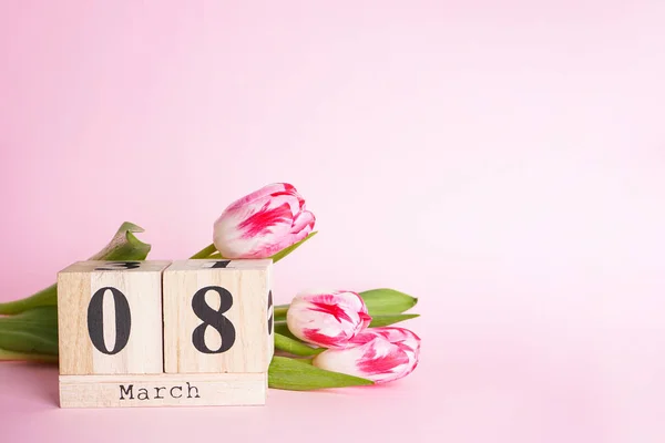 テキストのためのスペースを持つピンクの背景に木のカレンダーとチューリップとフラットレイアウトの組成 3月8日 — ストック写真