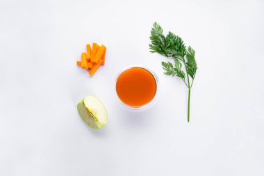 Düz kompozisyon, taze havuç suyu, dilimlenmiş havuç ve beyaz arka planda elma..