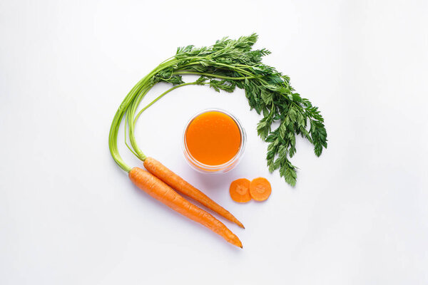 Flat composition with ripe fresh carrots and carrot juice on a white background