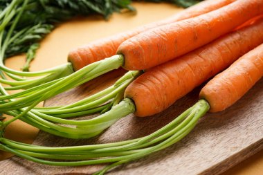 Ahşap mutfak tahtasının üzerinde kahverengi arkaplanlı taze havuçlar. Yakın çekim bileşimi.