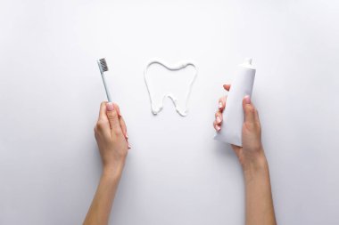 Sabah konsepti, diş macunu ve diş fırçası beyaz arka planda genç bir kadının ellerinde.. 