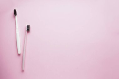Pembe arkaplandaki yazı için alanı olan iki diş fırçası..