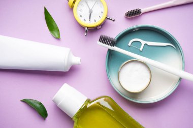 Sabah konsepti, çalar saat ve mor arka planda yakın plan diş fırçaları. Diş ve sağlık sigortası konsepti. Düz yatıyordu