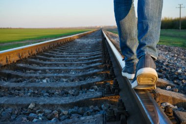 Genç adam tren yolu boyunca gidiyor..