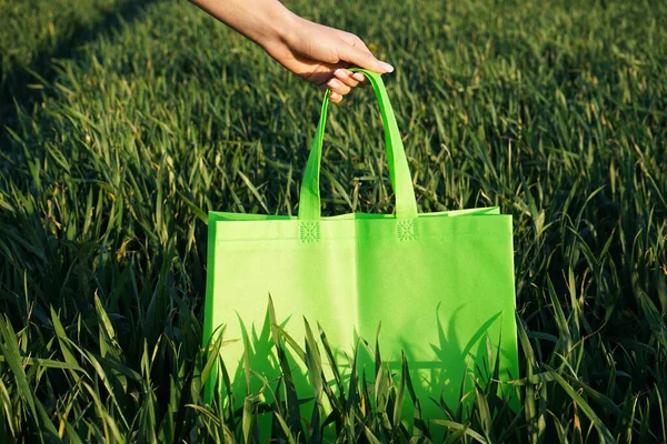 Eco-bag. Woman holding an eco bag outdoors, layout for design. Field of wheat.