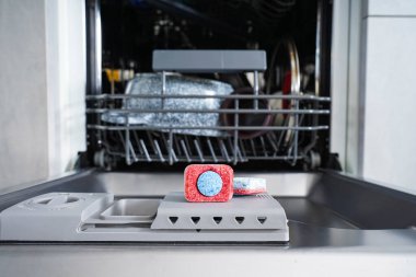 Plastik bulaşık kabında çok renkli bulaşık makinesi tableti. Yakın plan..