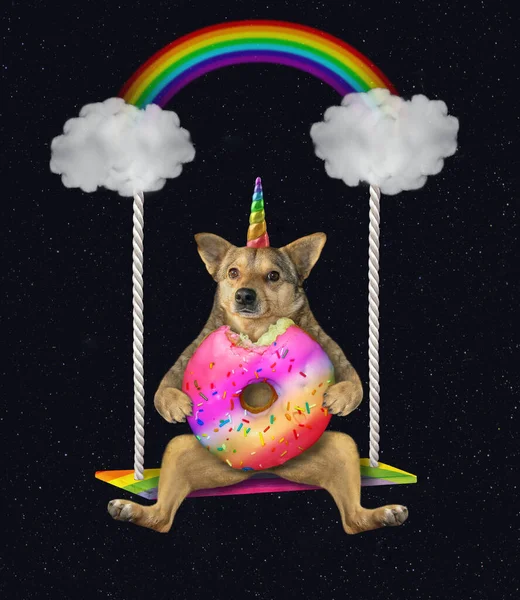 Beige Hondeneenhoorn Met Een Roze Donut Rijdt Nachts Een Wolkenschommel — Stockfoto