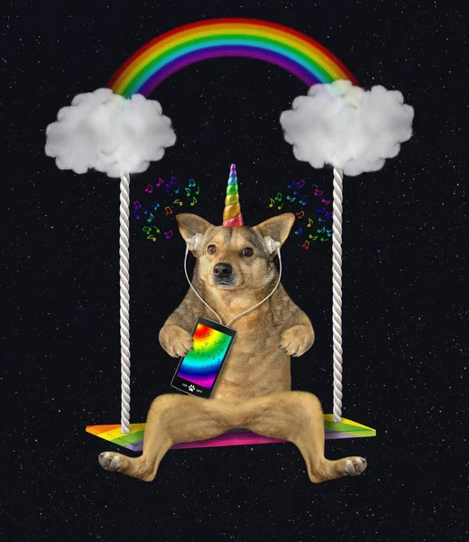The beige dog unicorn is listening to music from a smartphone on a cloud swing under the rainbow at night. Stars background.