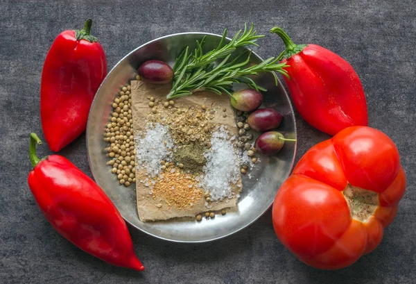 Яркий красный перец, специи и оливки на темном столе . — стоковое фото