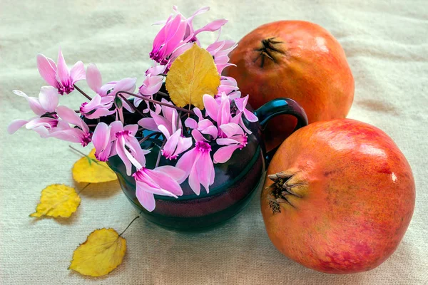 Pomegranate, flowers and autumn leaves on a white background.