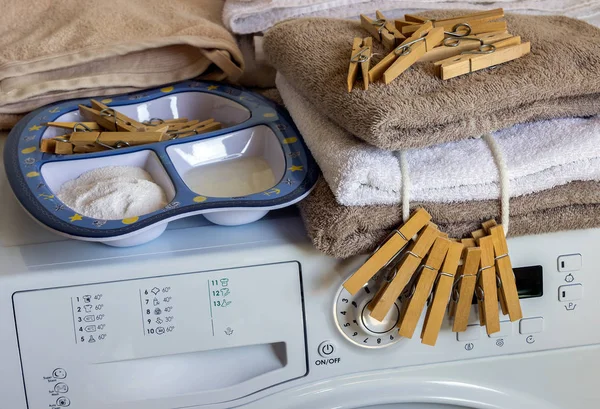 Auf der Waschmaschine liegen saubere Handtücher, Wäscheklammern und Waschmittel. — Stockfoto