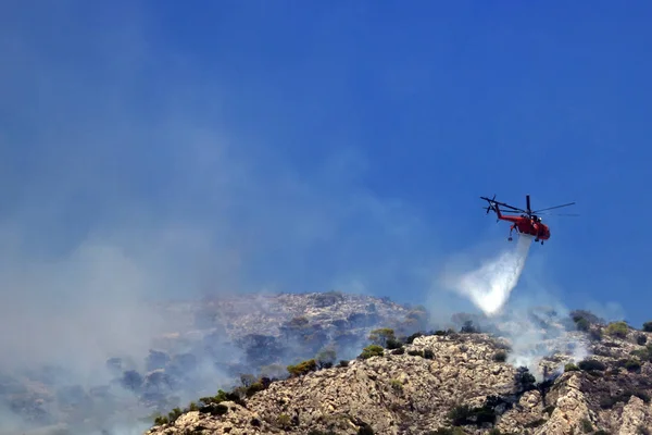 Fire helicopter extinguishes the fire on the hillside .