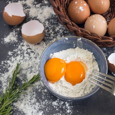 Yumurta ve un mavi kapta. Ev pişirme için malzemeler. 