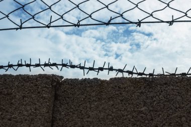 Mavi gökyüzüne karşı bir çit dikenli tel. 